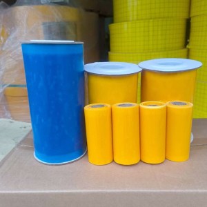 Tall blue canister beside yellow containers and small yellow cylinders on a cardboard surface in a warehouse setting.